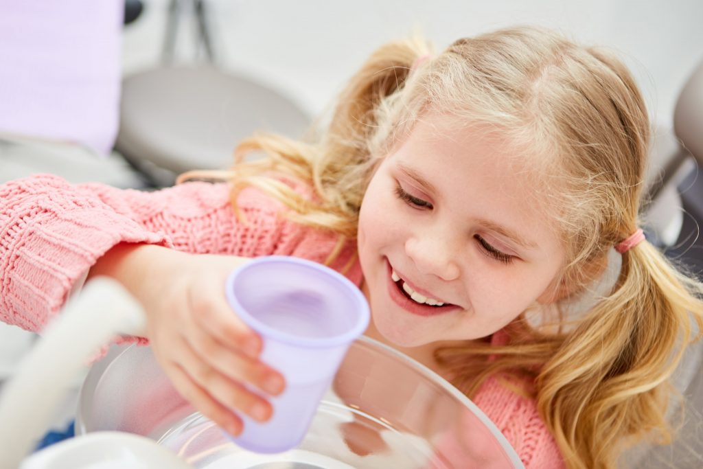 Mädchen spült den Mund aus beim Kinderzahnarzt
